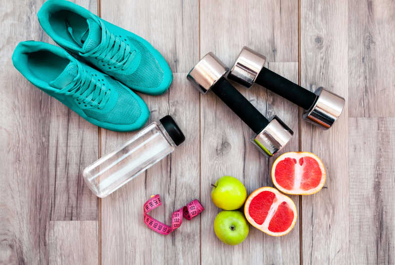 木桌上的健身器材运动鞋以及水果和卷尺