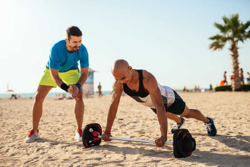 在海滩上健身的男子与教练