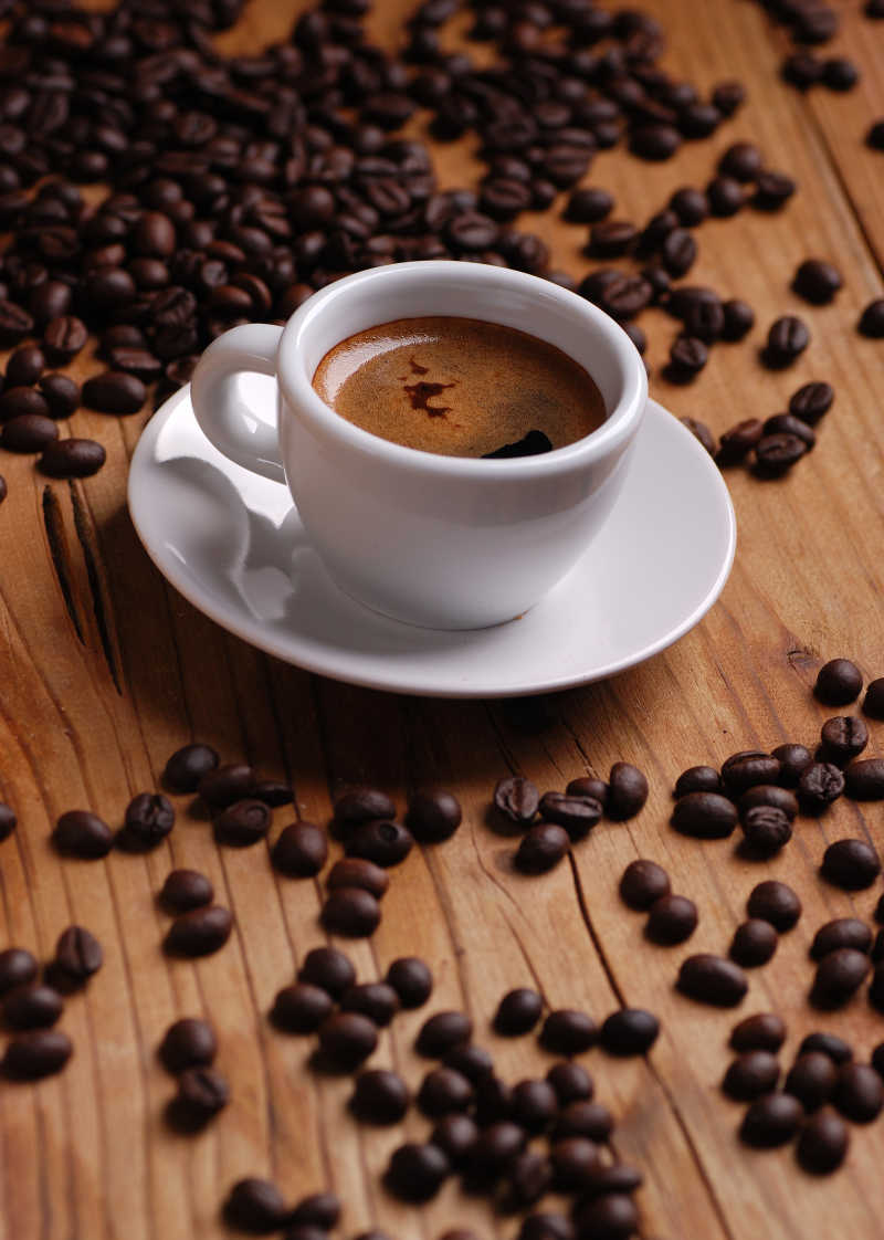 木桌上的一杯浓浓的咖啡与咖啡豆