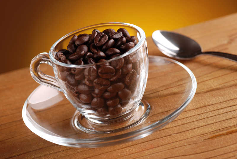 木桌上的玻璃杯上的咖啡豆