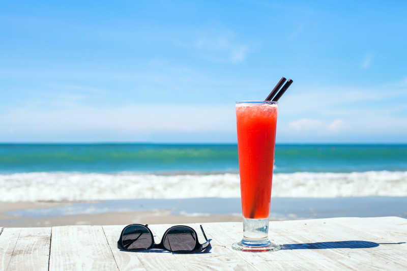 带鸡尾酒的背景和海滩上的太阳眼镜