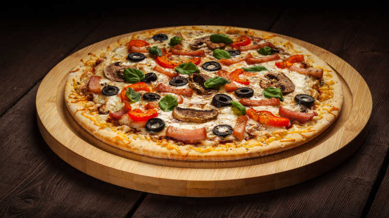 老餐桌木板上的火腿披萨