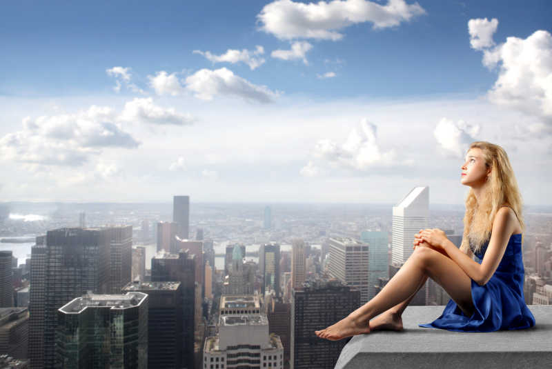穿着华丽衣服的年轻女子坐在摩天大楼的屋顶上