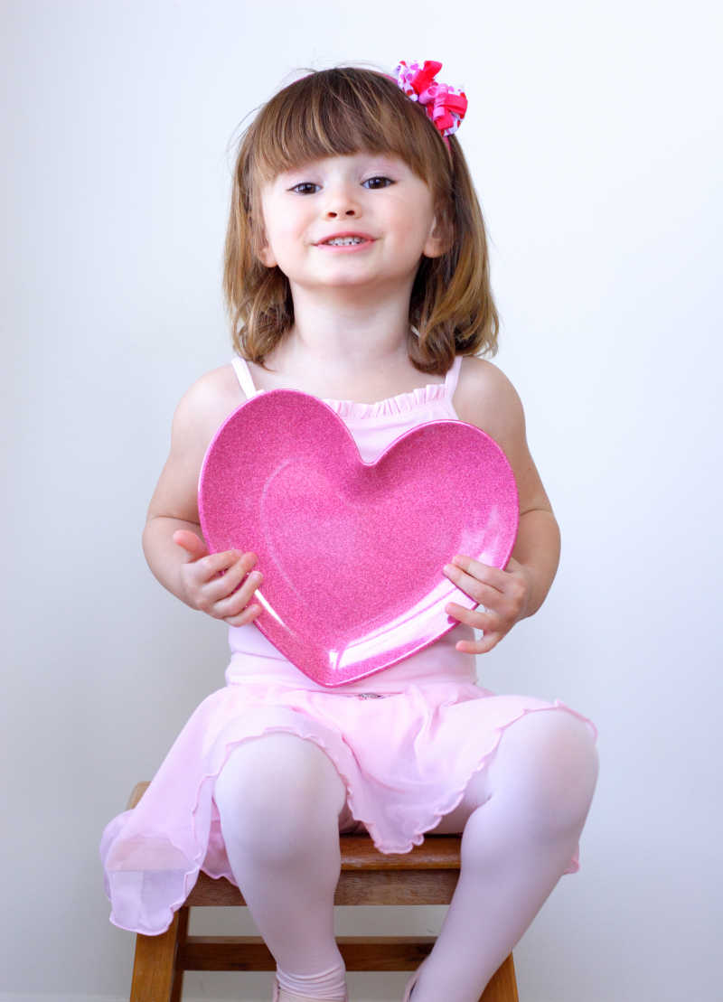穿粉色舞蹈服的小女孩抱着一颗心