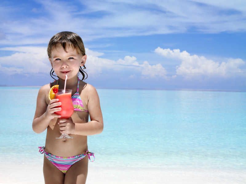 海滩边喝饮料的小女孩