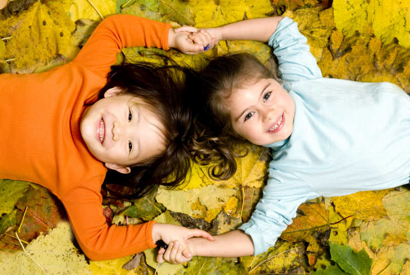 在秋叶上笑得开心的孩子们