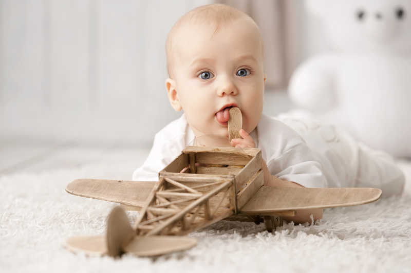 白色毛毯上可爱的小婴儿和他的玩具飞机
