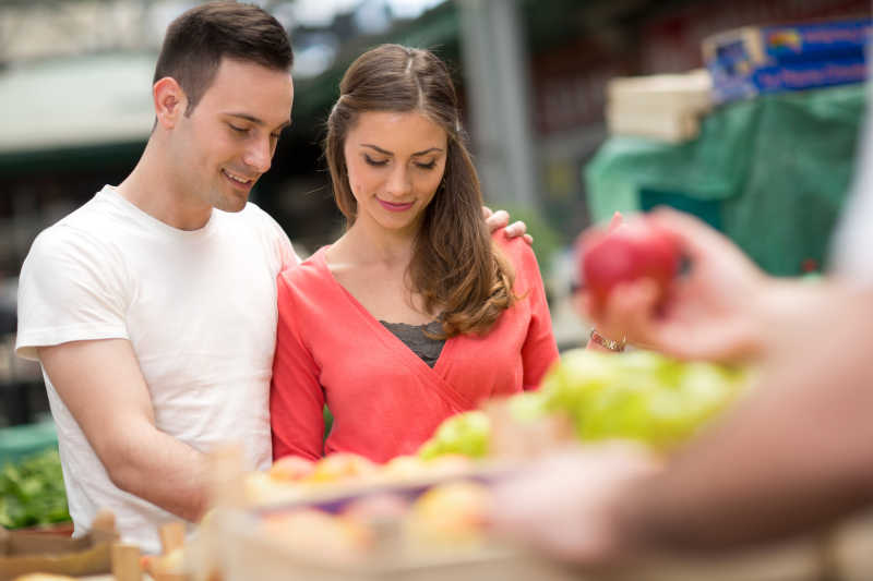 情侣夫妇在杂货店挑选健康的苹果
