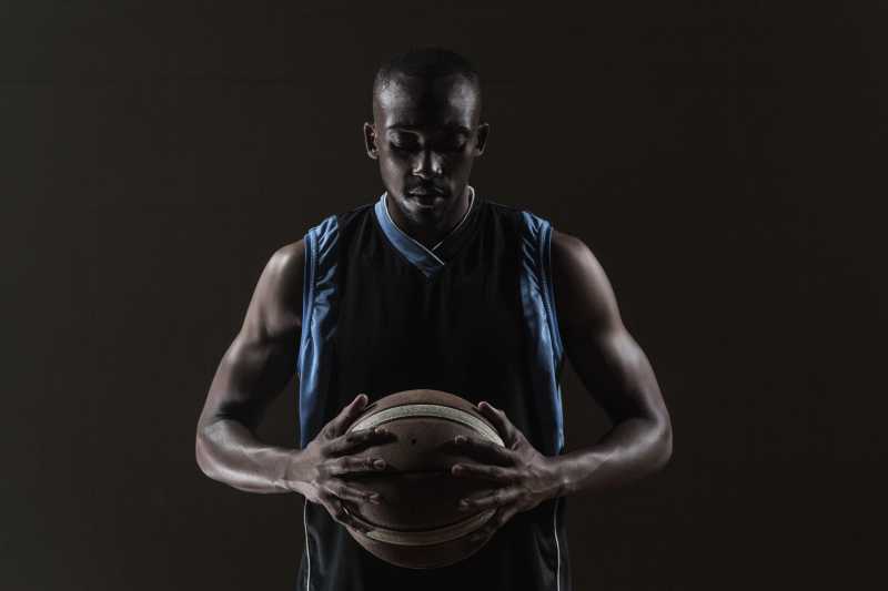 黑色背景下的篮球运动员双手握球