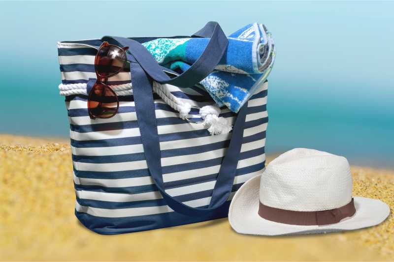 沙子上的草帽和旅行包
