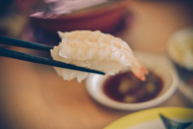 用筷子夹着鲜虾寿司
