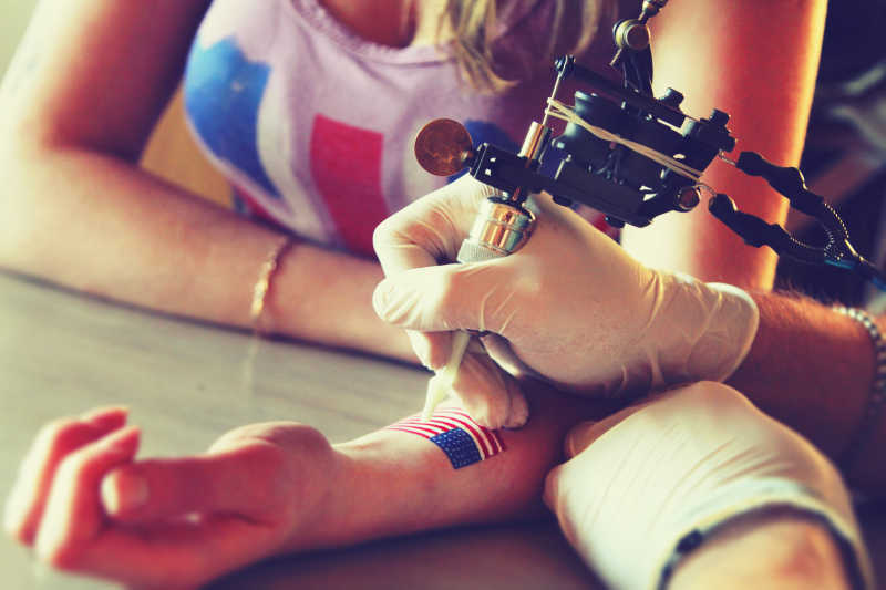 纹身师展示在金发的女孩手上绘制的纹身过程