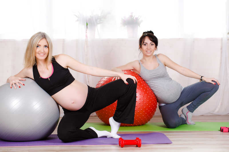 健身房联系瑜伽动作的两位孕妇