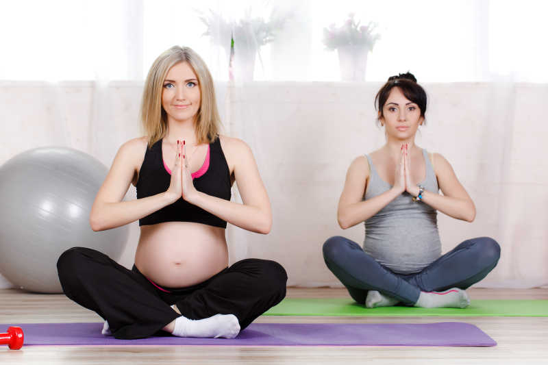 健身房进行瑜伽健身的两位孕妇