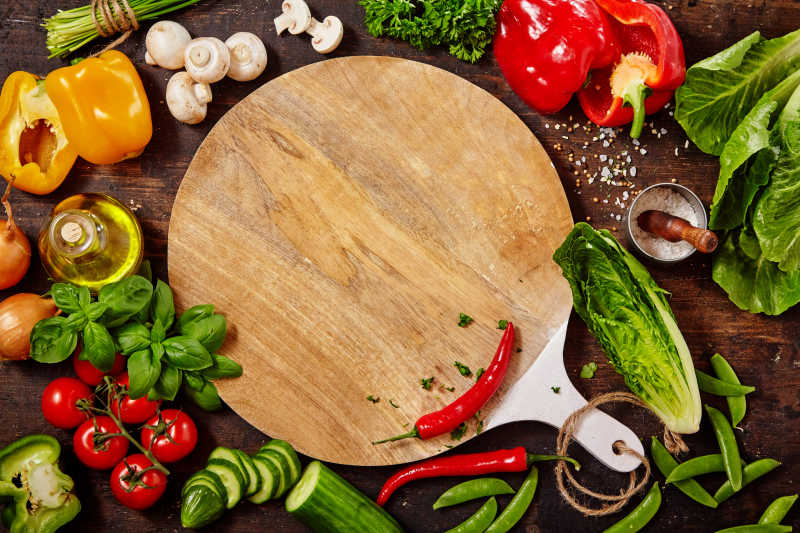 砧板周围新鲜的生蔬菜和各种药草和香料在质朴的木桌上