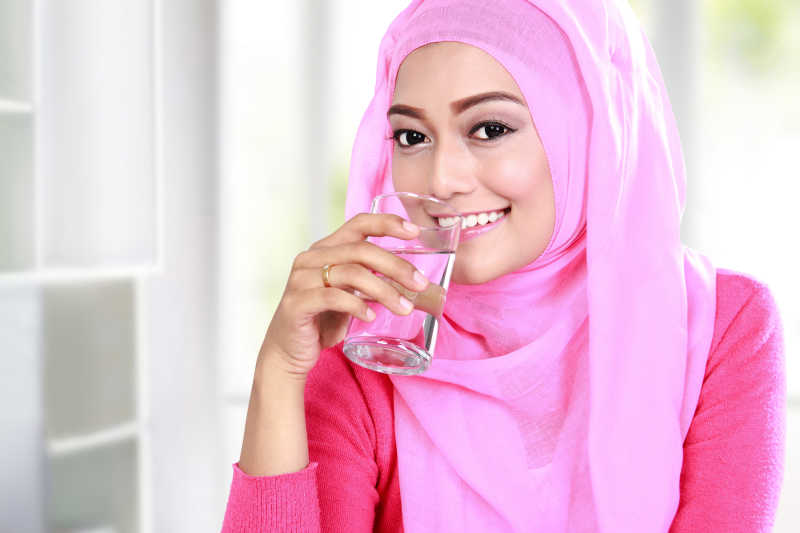 年轻的穆斯林妇女在喝水