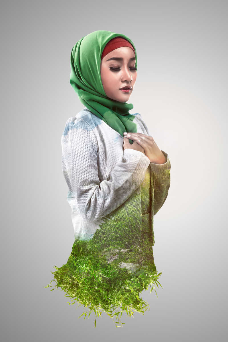 灰色背景下绿色草地和双重曝光的穆斯林女性形象