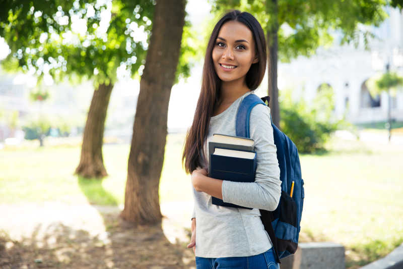 背着书包抱着书微笑的女学生