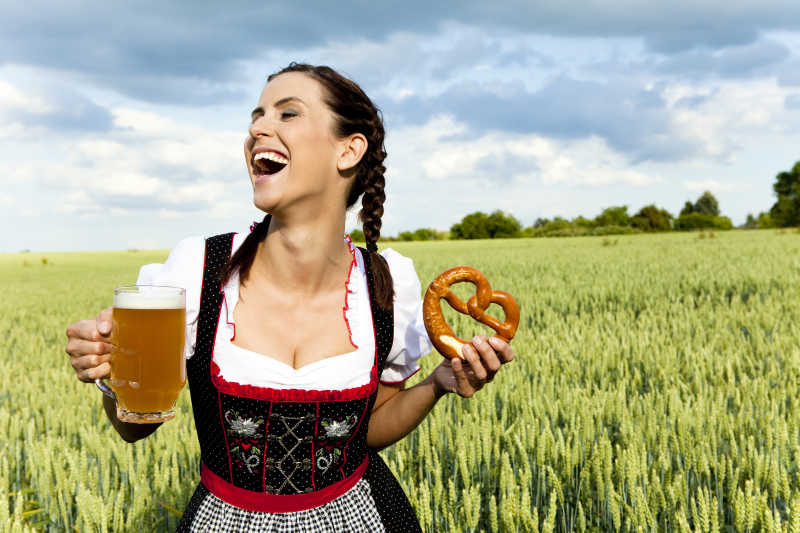 异国风情的微笑女子拿着啤酒在麦地里