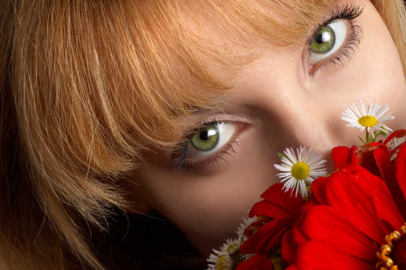 漂亮女孩的绿色的眼睛和红色的花朵