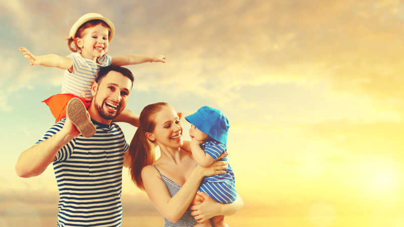 日落时分海滩上快乐的父亲母亲和两个孩子
