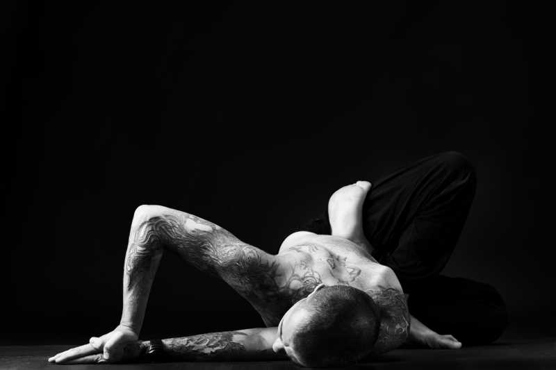 黑色背景下纹身的男人在做瑜伽