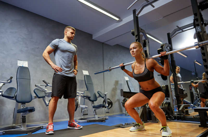 男教练和女子与健身房伸缩肌肉