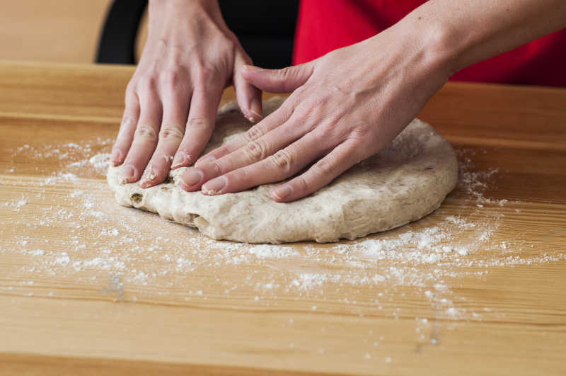 把面团放在木板上揉捏制作面包