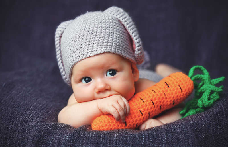 抱着胡萝卜的可爱婴儿