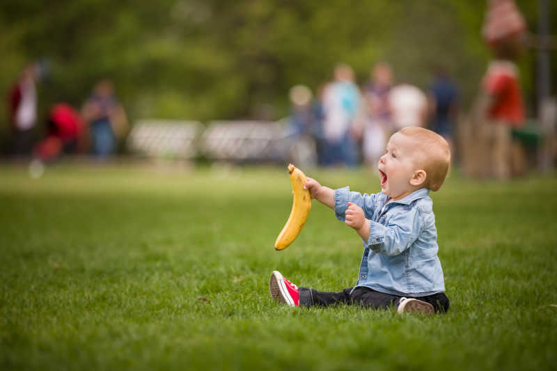 坐在草地上拿着香蕉的宝宝