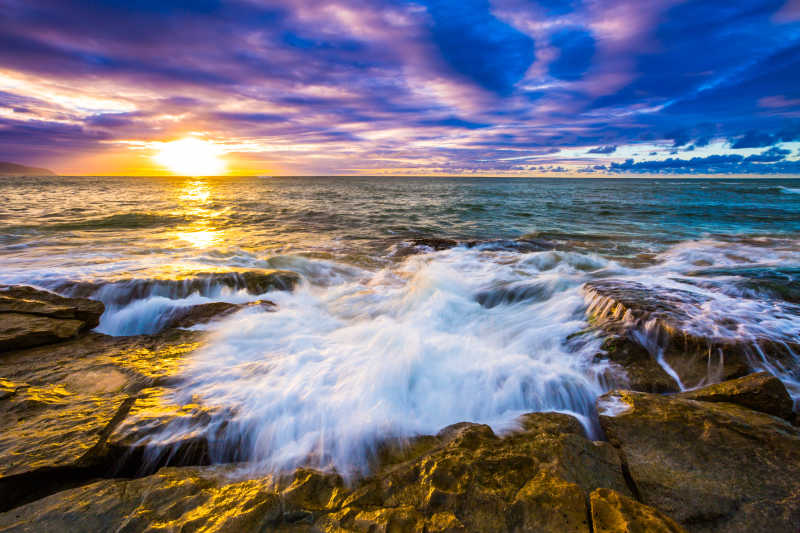 日落时分下海水冲击着岩石