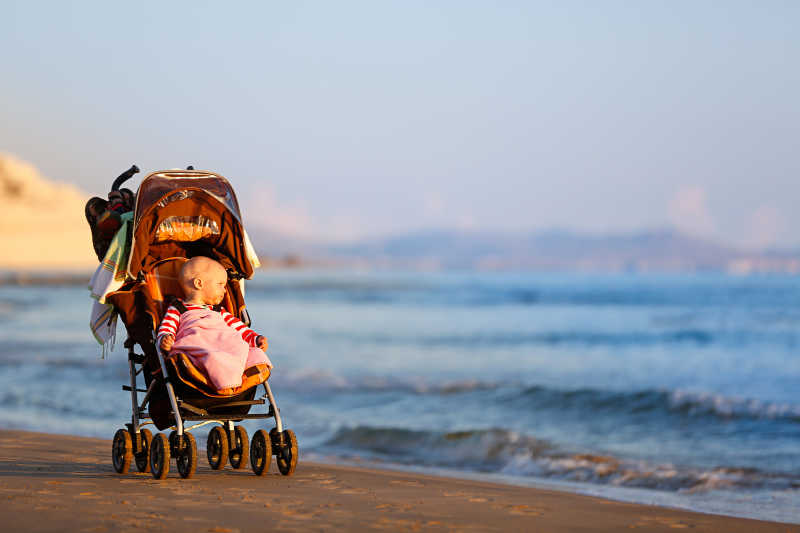 婴儿坐在婴儿车里观看海边的风景