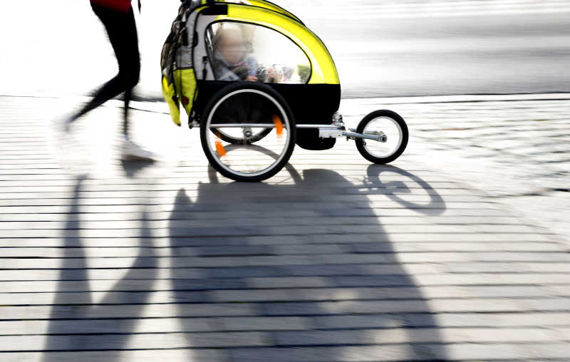年轻的母亲推着婴儿车在公园散步
