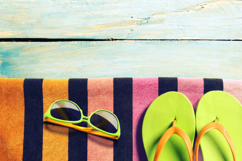 木板上的绿色拖鞋与太阳镜