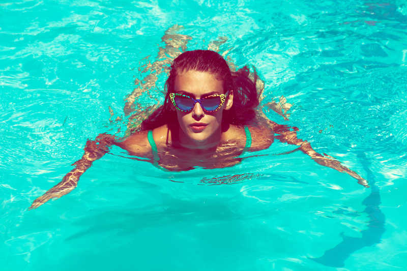 泳池里戴着墨镜游泳的性感美女