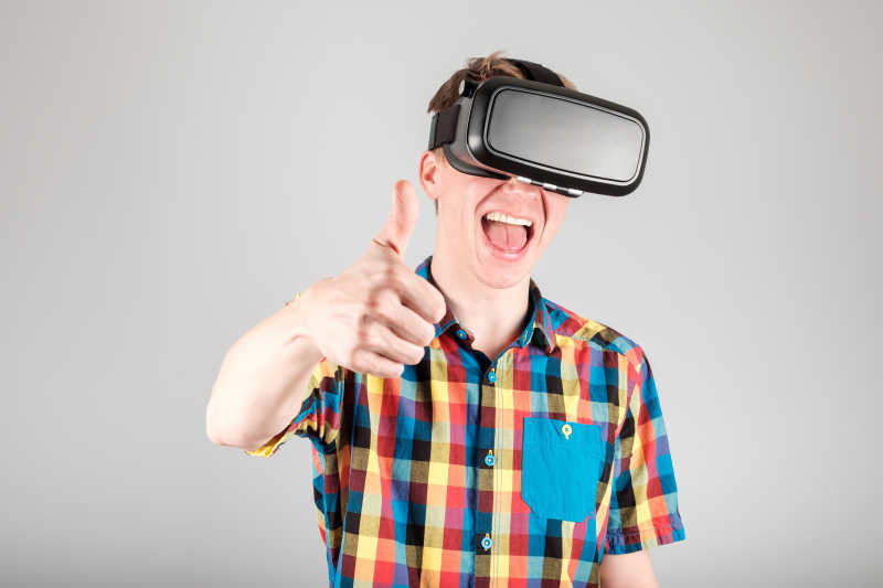 灰色背景前带着3D虚拟眼镜惊喜竖大拇指的男人