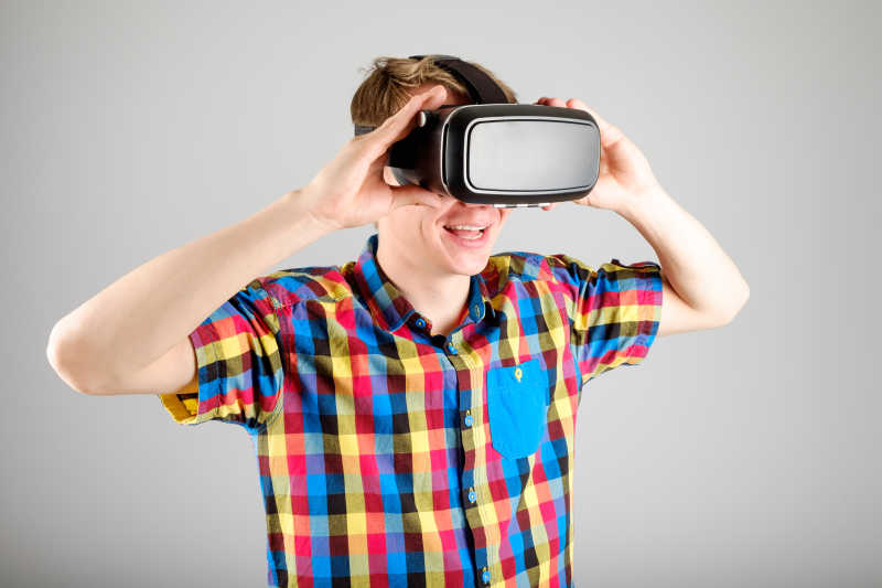 灰色背景下带着3D虚拟眼镜的格子衫男人