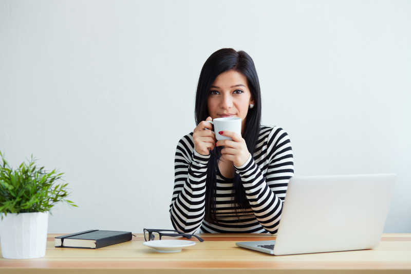 坐在办公桌前喝咖啡的年轻女性