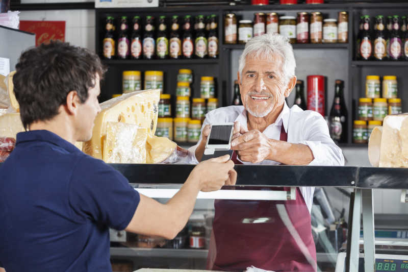 奶酪店里顾客和售货员正在用手机付款