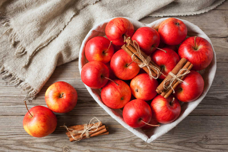 木质桌上的红苹果和肉桂