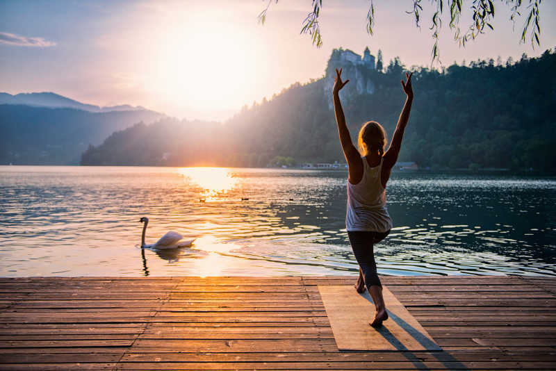 夕阳下湖边做瑜伽的年轻女子