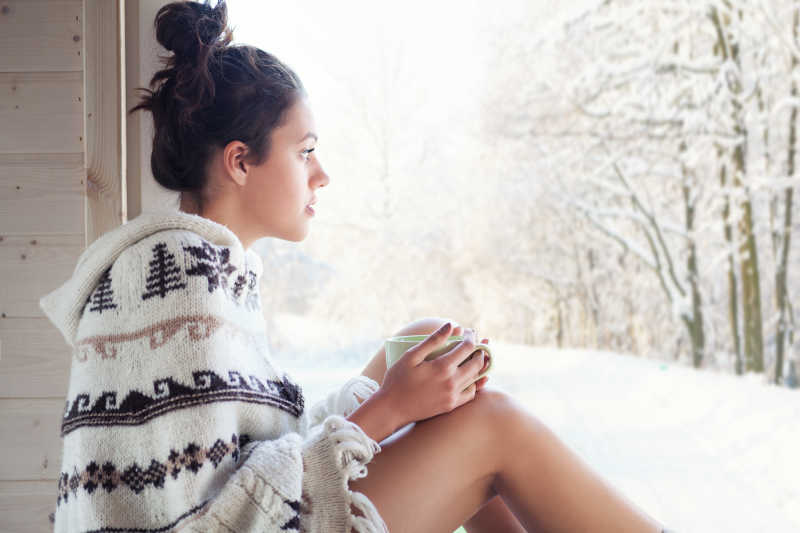 冬日坐在窗外的年轻快乐女性
