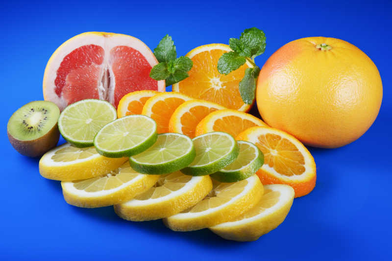 蓝色背景下的柑橘柚子柠檬和猕猴桃