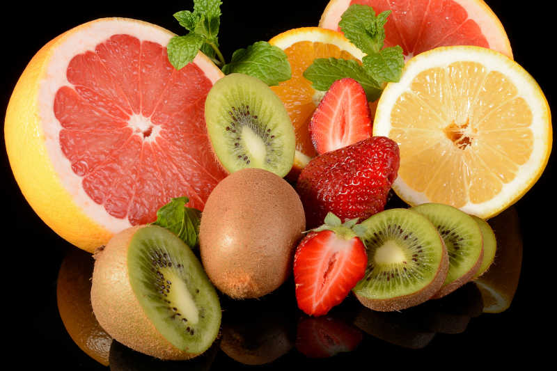 黑色背景下的草莓葡萄柚柠檬猕猴桃和橙子