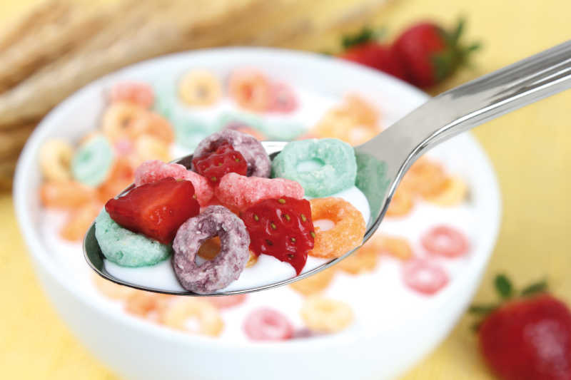 用勺子展示牛奶与燕麦圈草莓早餐
