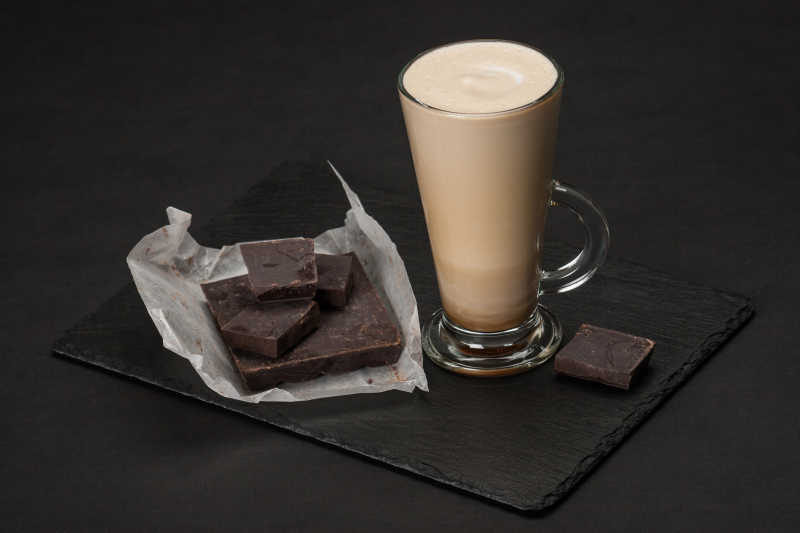 黑色背景下一杯咖啡与巧克力块
