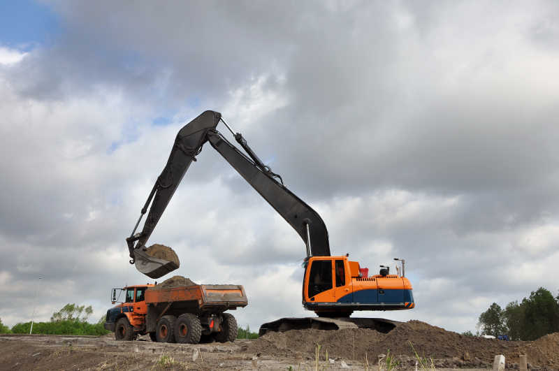 挖掘机正在给自卸车上装载土