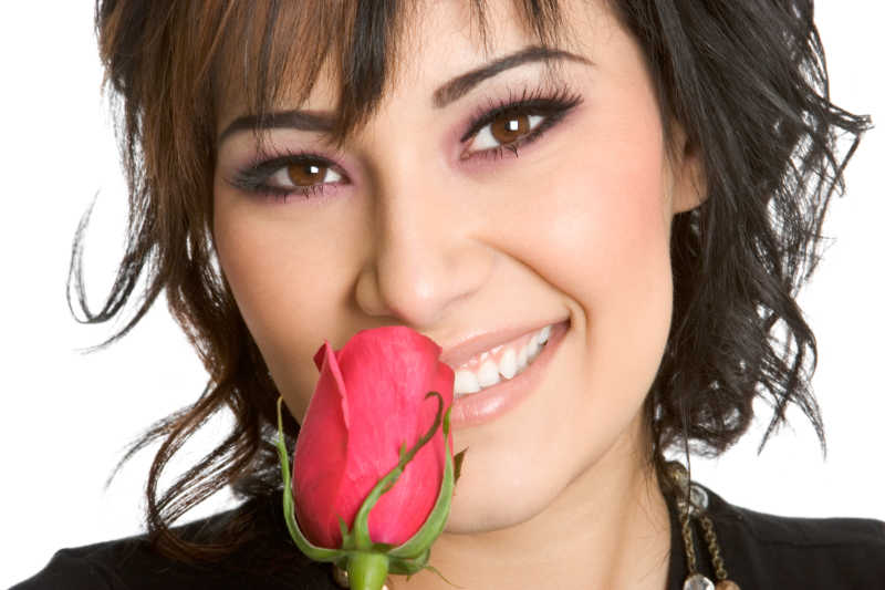微笑的女人拿着玫瑰花放在鼻子边闻