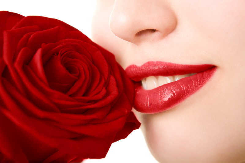 大红色的玫瑰花被女人放在嘴边闻着