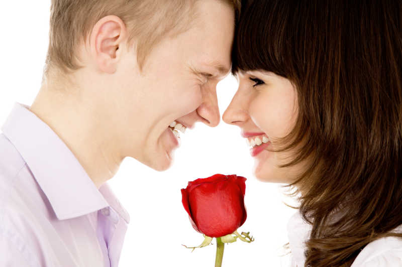 手中拿着玫瑰的男人和女人抵着头对视而笑
